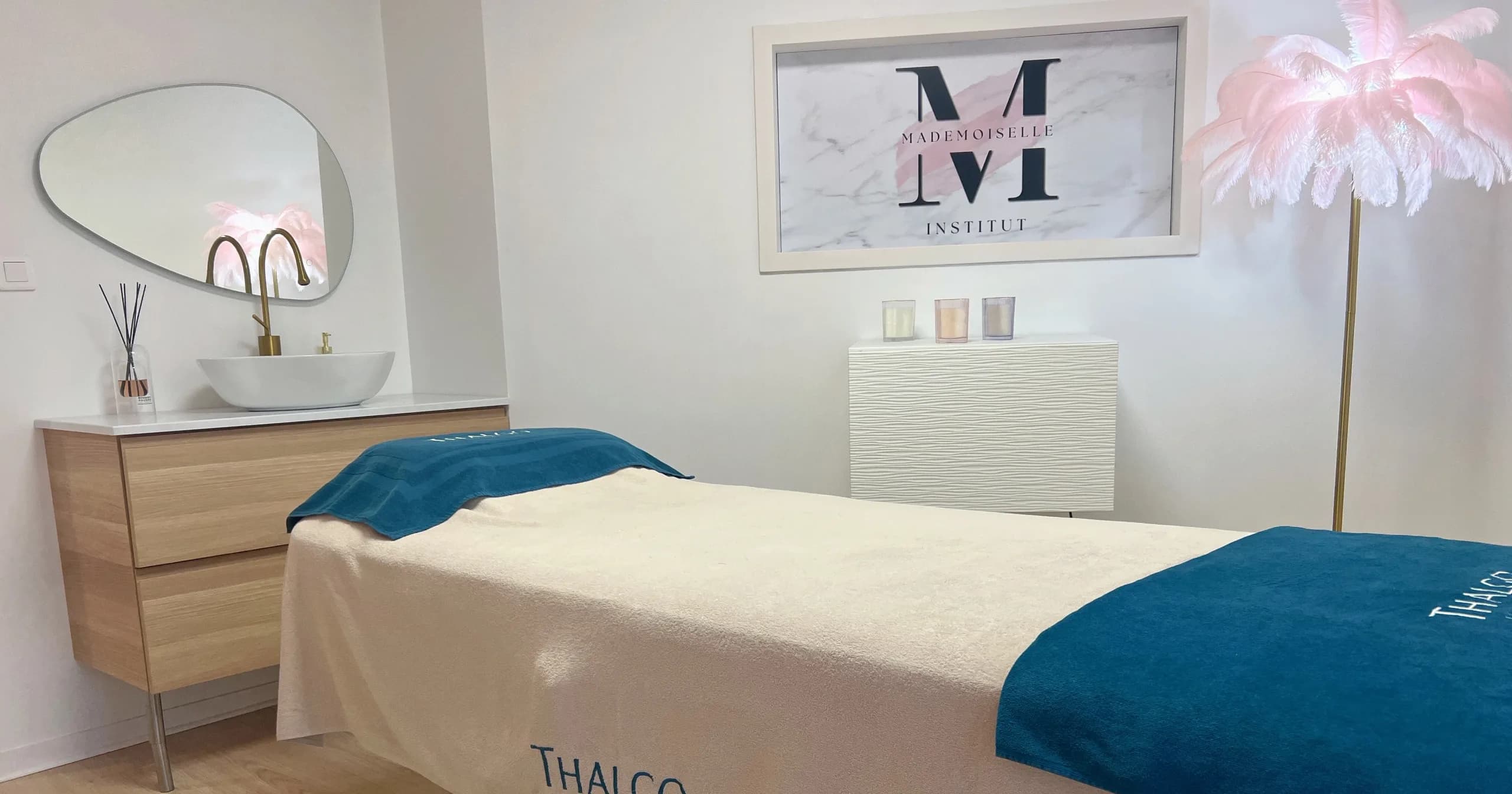 Cabine de soin avec serviettes Thalgo bleu canard et cadre du logo Mademoiselle M Institut